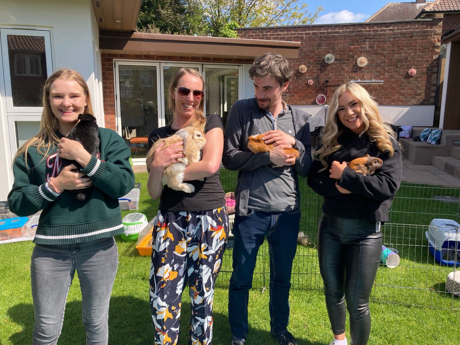 Four people holding rabbits